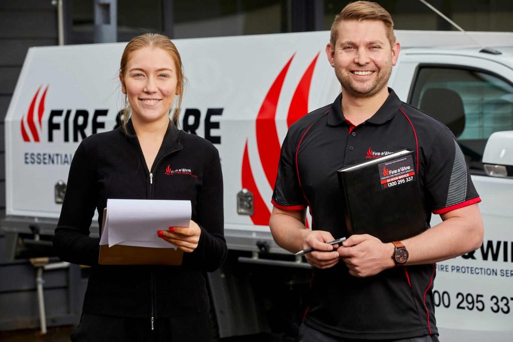 Two Fire and Wire employees standing in front of a Fire and Wire work truck