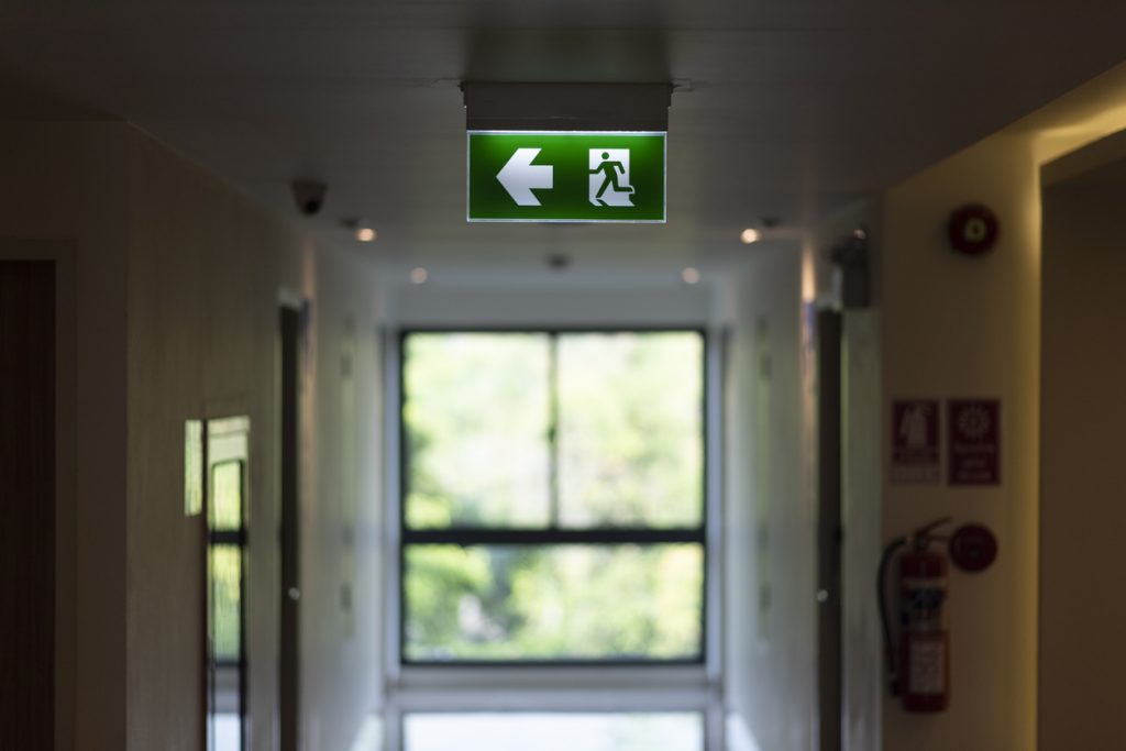 An illuminated emergency exit sign on an office building ceiling